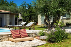 A poolside area with lounge chairs, a stone wall, and a stone bench with cushions. - Villa Franciska (Istria - Svetvinčenat) (Svetvinčenat)