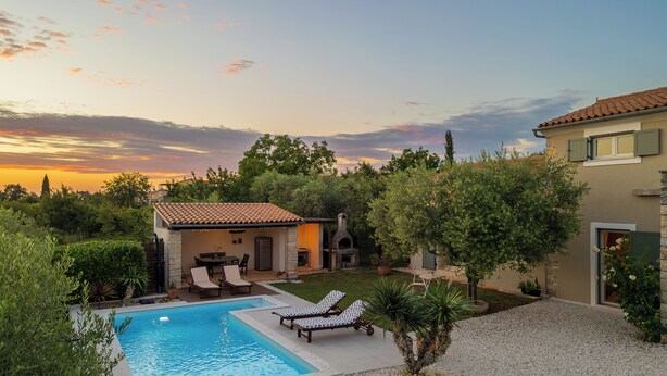 Un patio trasero con piscina, mobiliario exterior y zona de barbacoa.