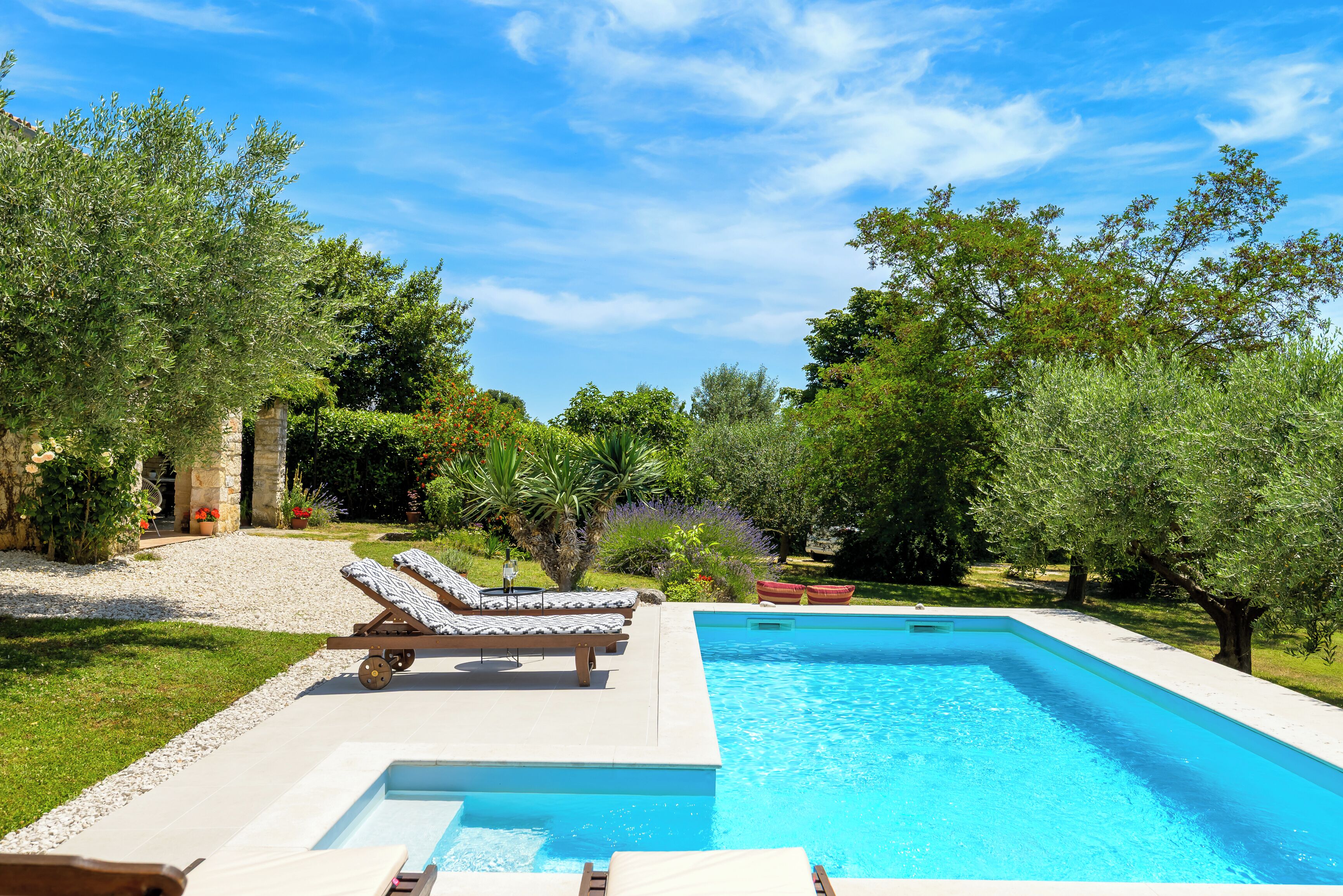 Una piscina amb dues gandules i una paret de pedra.