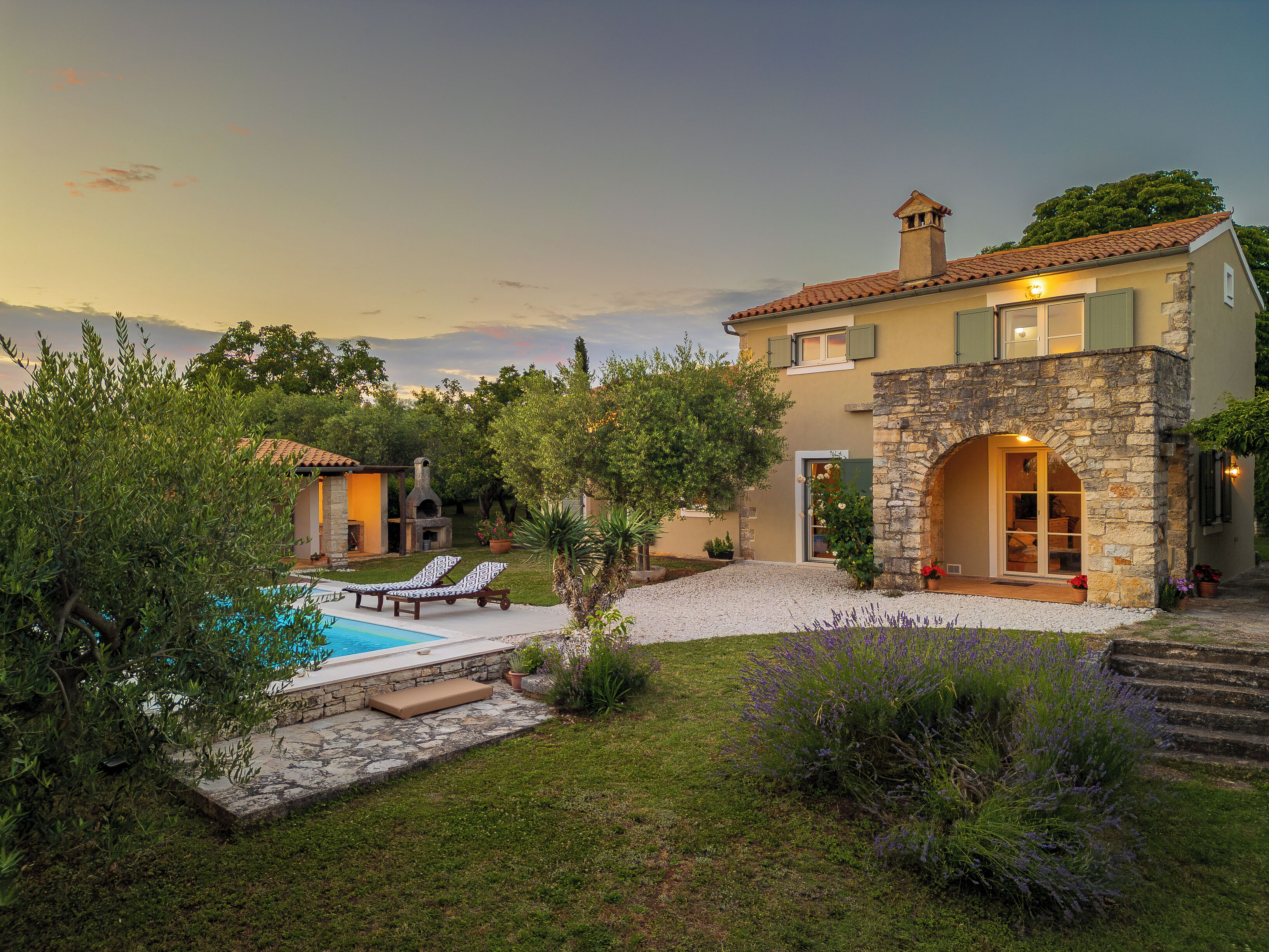 Una villa con piscina, zona de estar al aire libre y un arco de piedra.