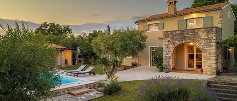 Una villa con piscina, zona de estar al aire libre y un arco de piedra.