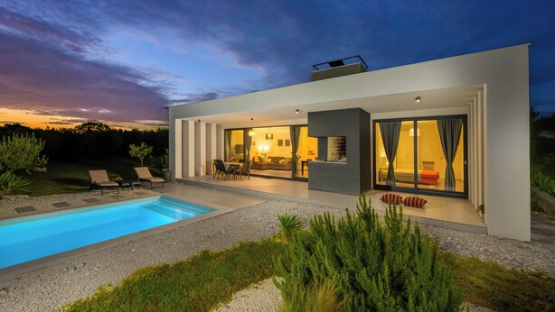 Una casa moderna con piscina, mobiliario exterior y un amplio ventanal que da al interior.