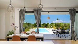 Un comedor moderno con vistas a la piscina, con una mesa para dos, sillas y una mesa de comedor.