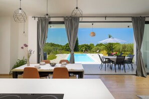 Ein stilvoller Essbereich mit Blick auf einen Pool, ausgestattet mit einem Tisch für zwei Personen, Stühlen und einem Esstisch.