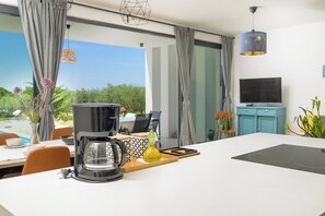 A modern kitchen with a coffee maker, a TV, and a view of the outdoors. - Villa Vinci (Istria - Svetvinčenat) (Svetvinčenat)