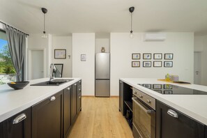A modern kitchen with a central island, stainless steel appliances, and a minimalist design. - Villa Vinci (Istria - Svetvinčenat) (Svetvinčenat)