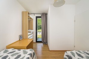 Ein gemütlicher Raum mit Bett, einer Holzbank, einem Kleiderschrank und Blick durch eine Tür.