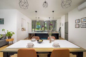 Un espace de salle à manger moderne avec une grande table, des chaises et des luminaires suspendus.
