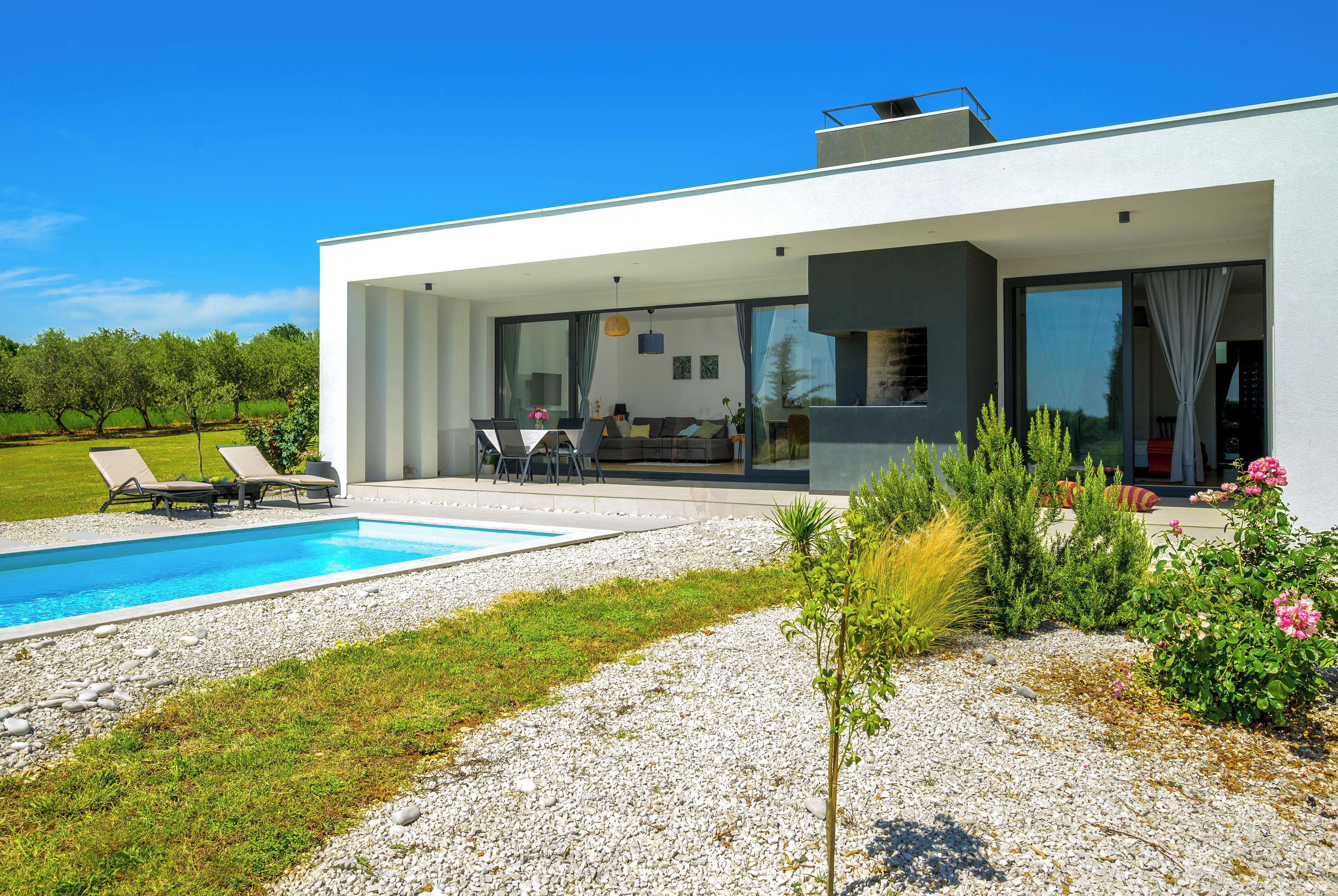 A modern house with a swimming pool, outdoor seating, and a garden.