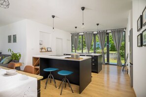 Une cuisine moderne dotée d’un îlot central, de tabourets de bar et d’un coin repas avec une table et des chaises.