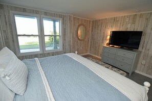 A bedroom with a bed, a dresser, a television, and a window. - Kismet - Oceanfront in Garden City Beach (Garden City Beach)