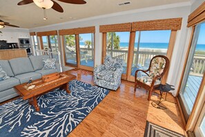A spacious living area with a view of the beach, a kitchen with an oven, and a ceiling fan. - Kismet - Oceanfront in Garden City Beach (Garden City Beach)