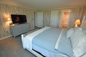 A bedroom with a bed, a television, a dresser, and a door leading to a bathroom. - Kismet - Oceanfront in Garden City Beach (Garden City Beach)