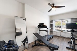 A home gym with a treadmill, bench press, and dumbbells. - Stylish Scottsdale Home with Pool & Hot Tub! Prime location! Family friendly!  (Scottsdale)