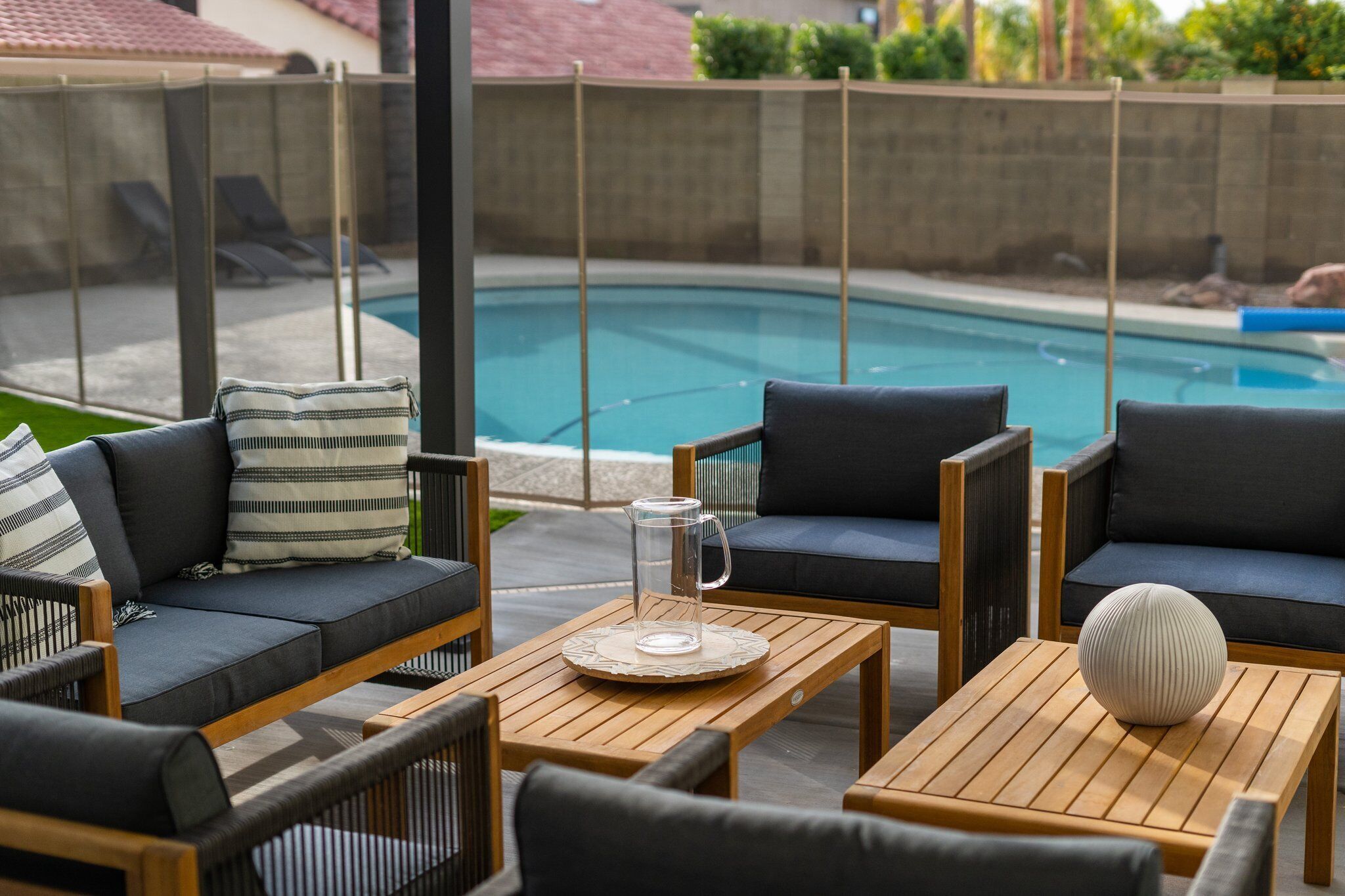 A poolside seating area with a pool in the background.
