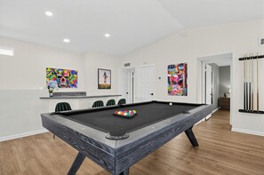 A pool table in a room with a wooden floor, white walls, and a door leading to another area. - Stylish Scottsdale Home with Pool & Hot Tub! Prime location! Family friendly!  (Scottsdale)