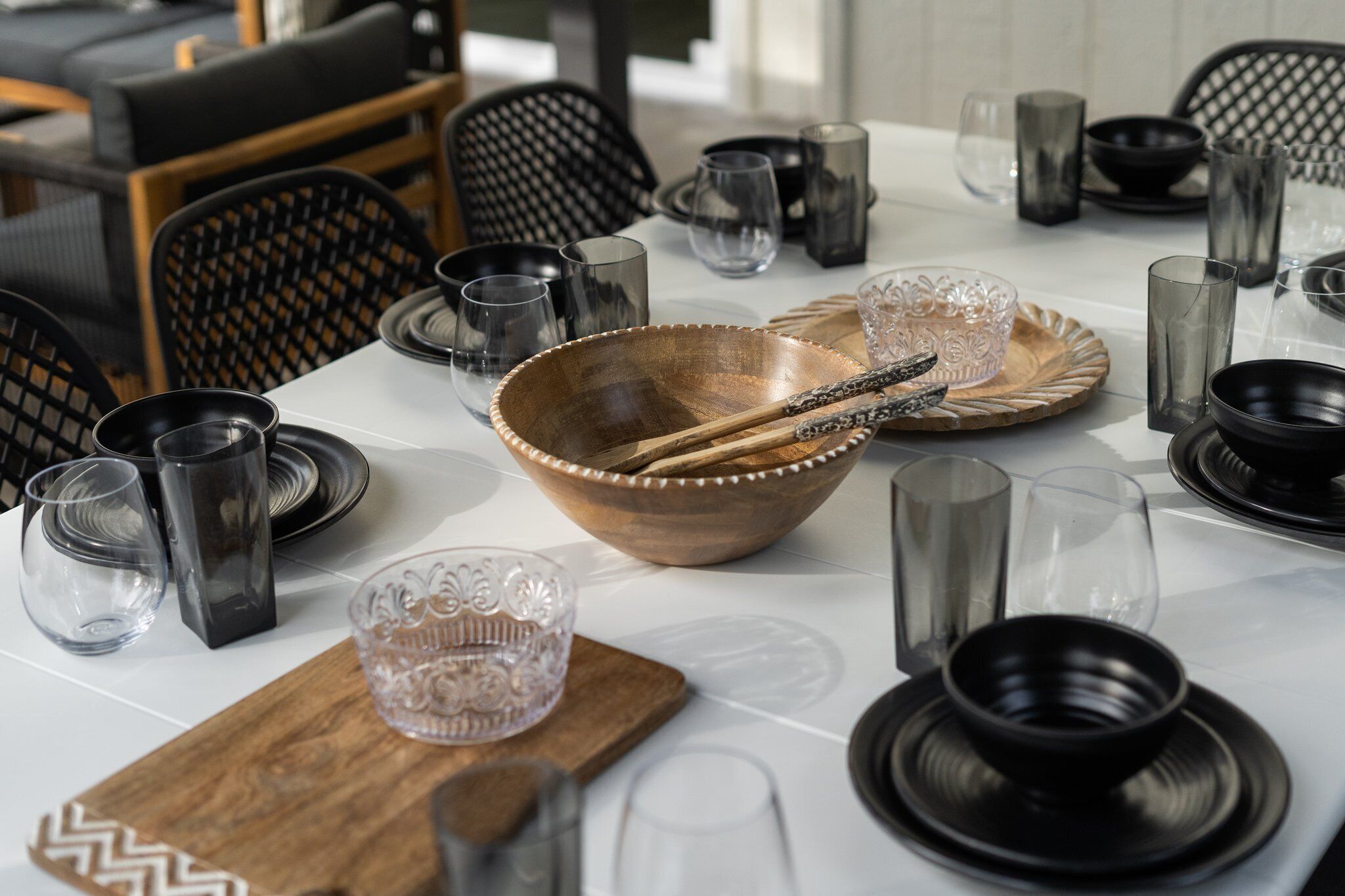 Een eettafel gedekt met divers servies, glazen en bestek, omringd door stoelen.