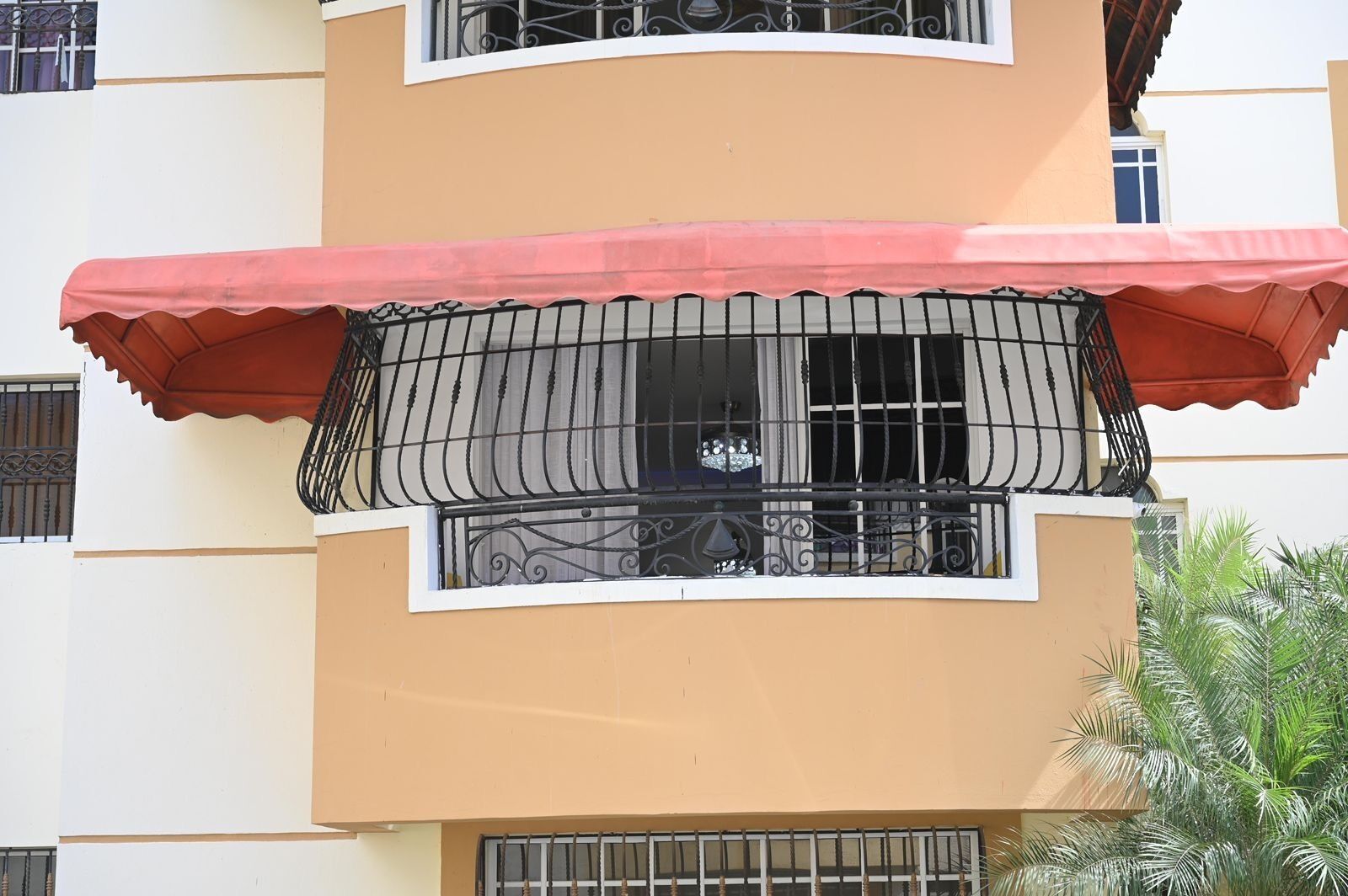 A multi-story building with balconies, a red awning, and barred windows.
