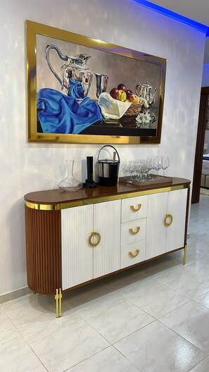 A modern interior with a white and gold cabinet, a painting above it, and a blue-lit wall. - Apartment Charming 3-bedroom family apartment home in Santiago de los Caballeros (Santiago de los Caballeros)