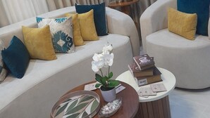 Een moderne woonkamer met een bank, twee fauteuils, een salontafel en een lamp.