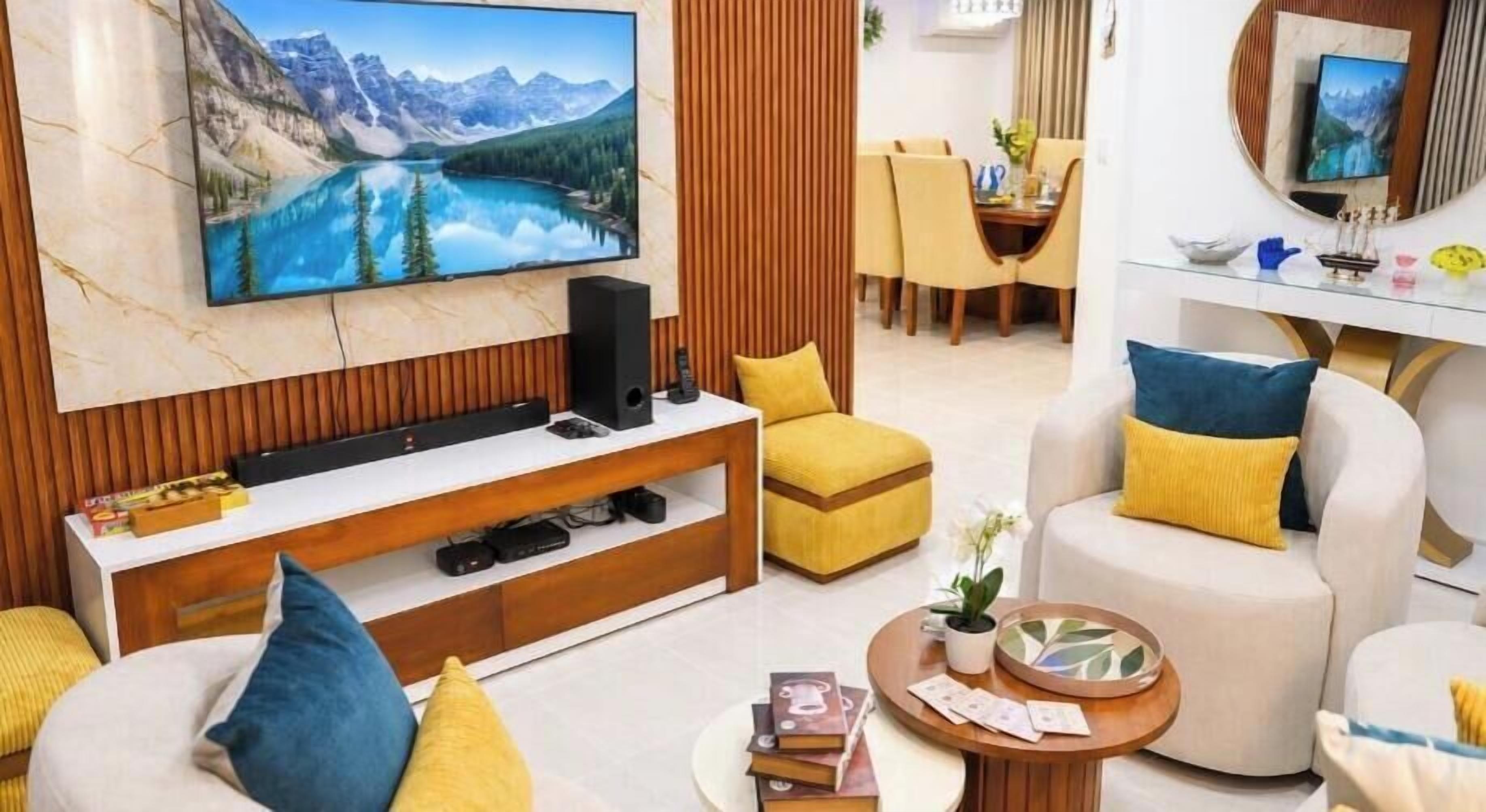 Una sala de estar moderna con un televisor de pantalla plana, asientos cómodos, una mesa de centro y un comedor al fondo.