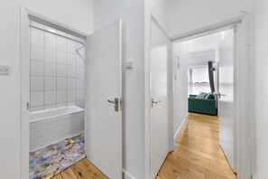 A hallway with a tiled shower area and a wooden floor. - Modern 2BR Apartment | Sleeps 5 | Canary Wharf E14 (London)