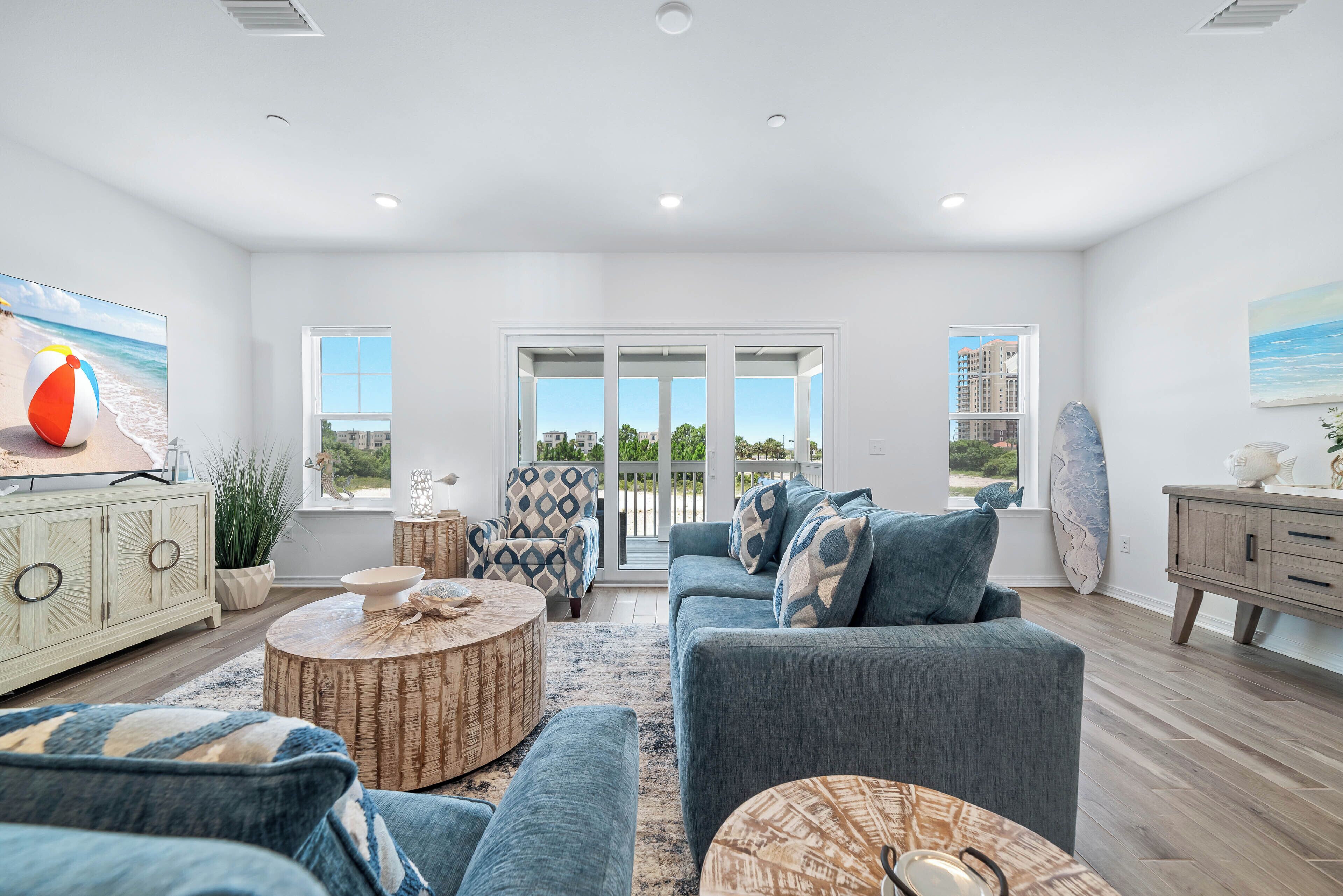 A spacious living room with a large sofa, a coffee table, and a view of the ocean through the windows.