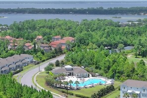 Un quartier résidentiel doté d’une grande piscine, entourée de maisons et d’une végétation luxuriante.