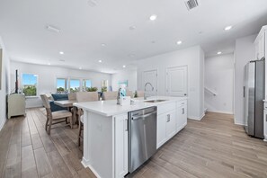 A modern kitchen with a dishwasher, a sink, and a stainless steel refrigerator. - Luxury Lost Key Retreat | Private Beach Club, Pools & Golf | BEACHBALL PROPERTIES (Pensacola)