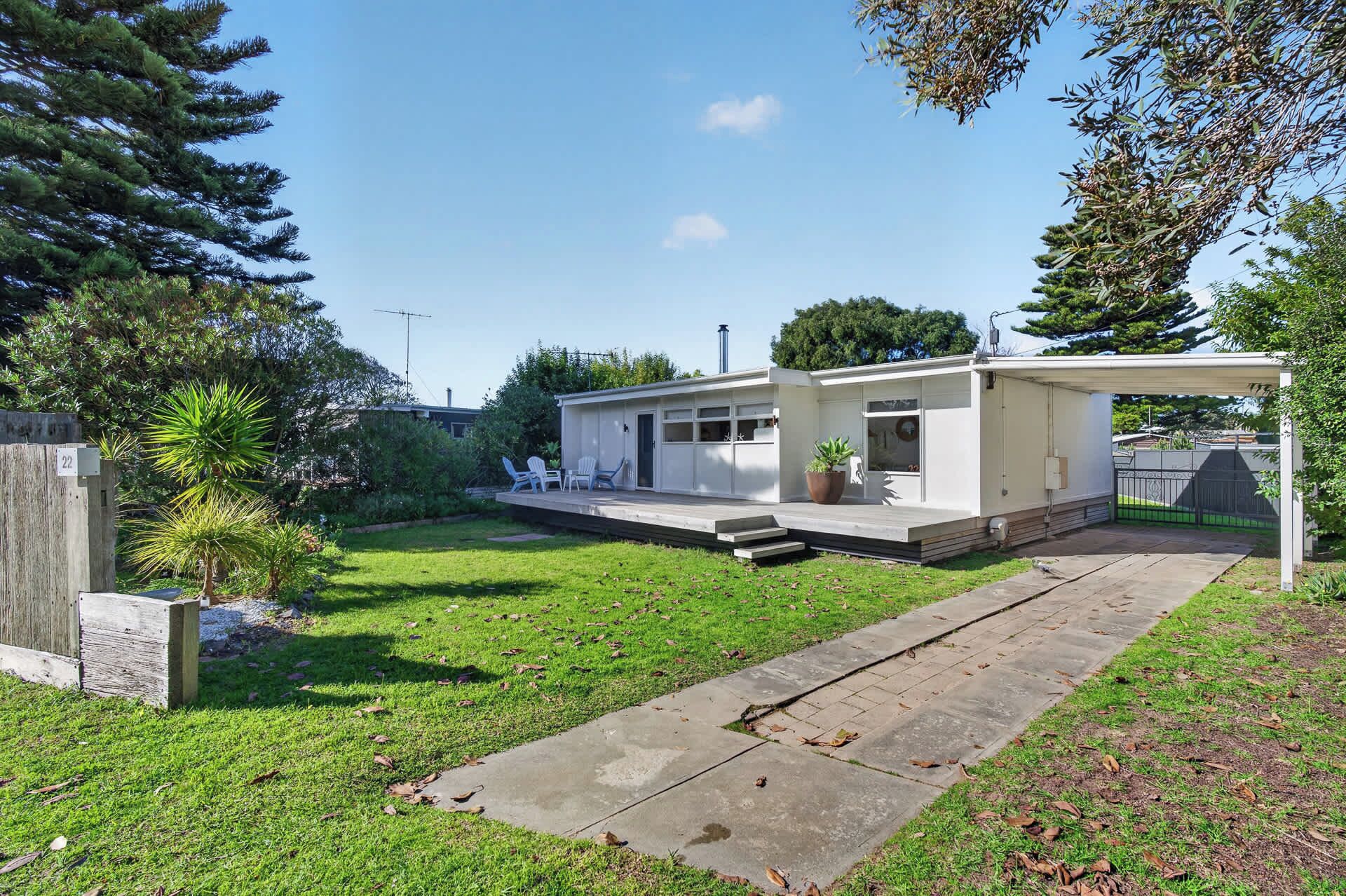 A modern single-story house with a covered patio, a small garden, and a paved driveway.