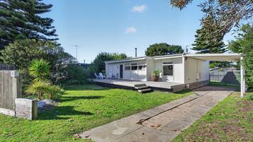 A modern single-story house with a covered patio, a small garden, and a paved driveway.