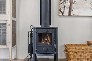 A black wood-burning stove with a glass door, a metal grate, and a chimney.