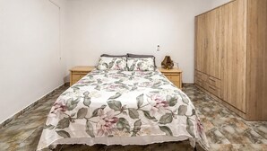 Ein Schlafzimmer mit einem Bett, Nachttischen, einem Kleiderschrank und einem Fliesenboden.