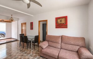 A living room with a sofa, a dining table with chairs, a ceiling fan, and artwork on the walls. - Lovely apartment in Los Alcázares with WiFi (Los Alcázares)