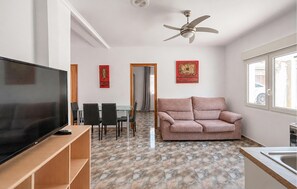 A modern living room with a flat-screen TV, a sofa, a ceiling fan, and a dining area with chairs and a table. - Lovely apartment in Los Alcázares with WiFi (Los Alcázares)