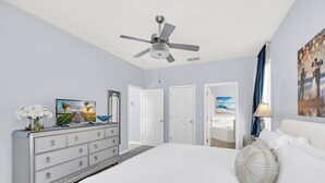 Ein Schlafzimmer mit einem großen Bett, einem Schminktisch, einem Deckenventilator und einem Gemälde an der Wand.