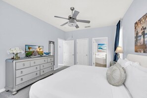 Ein Schlafzimmer mit einem großen Bett, einem Schminktisch, einem Deckenventilator und einem Gemälde an der Wand.
