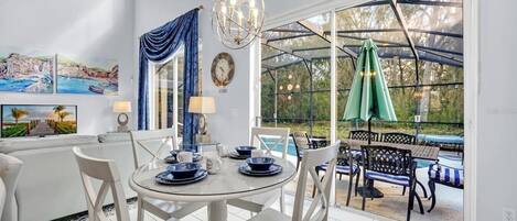 A dining area with a round table, chairs, and a view of an outdoor pool.