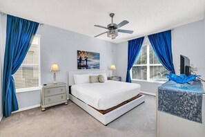 Ein Schlafzimmer mit Bett, Nachttischen, Deckenventilator und Schreibtisch mit Computer.