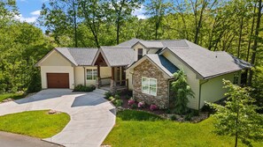 A two-story house with a garage, a stone accent wall, and a well-maintained lawn. - Summit Trails Sanctuary: 3bdrm. Sleeps 8, Hot Tub, One level, Pool Table (Sevierville)