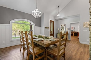 A dining area with a wooden table set for four, surrounded by wooden chairs, with a chandelier above. - Summit Trails Sanctuary: 3bdrm. Sleeps 8, Hot Tub, One level, Pool Table (Sevierville)