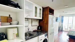 Cocina compacta con lavadora, microondas y lavabo.