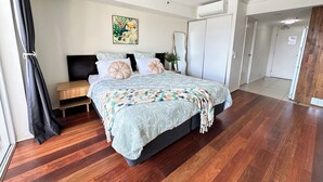 Un dormitorio con cama, ventilador de techo, puerta y ventana con cortinas.