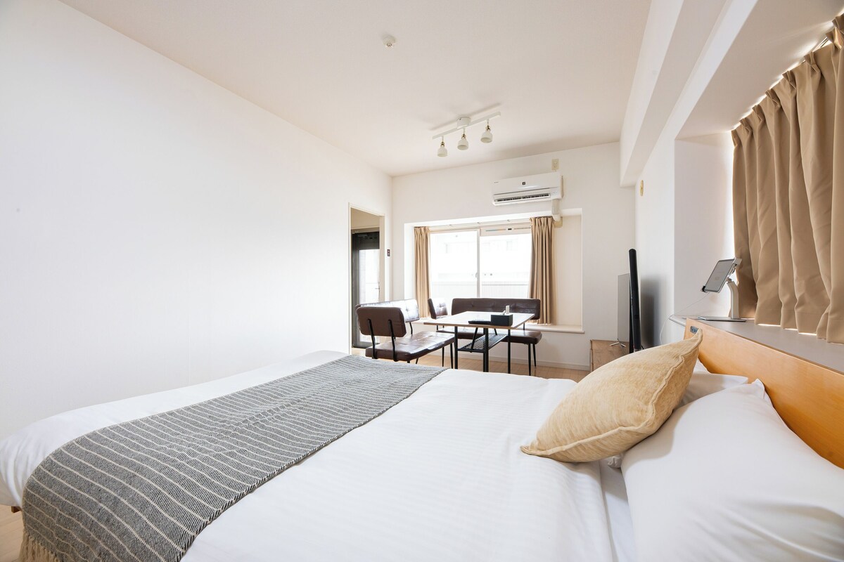 Een hotelkamer met een bed, bureau, stoel, televisie en een airconditioning.