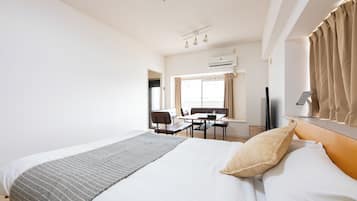 Habitación de hotel con cama, escritorio, silla, televisor y aire acondicionado.