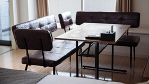 Un espace repas comprenant une table en bois, des chaises en métal noir et un banc.
