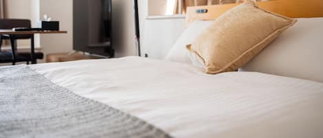 Una camera d'albergo con un letto, una scrivania, una televisione e una finestra con tende.