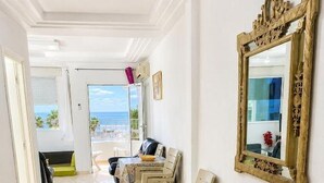 Un pasillo con un banco de madera, una mesa de comedor con sillas y un espejo grande en la pared.