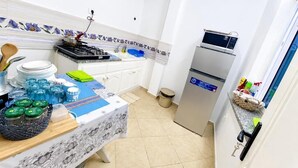 Una cocina compacta con estufa a gas, refrigerador y comedor con mesa lista para dos.