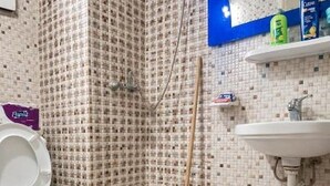 Un baño con inodoro, zona de ducha, lavabo y un trapeador.